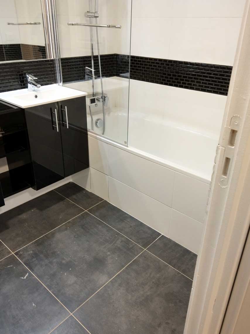Salle de bain avec baignoire et bordure en mosaïque noire — rénovation Paris