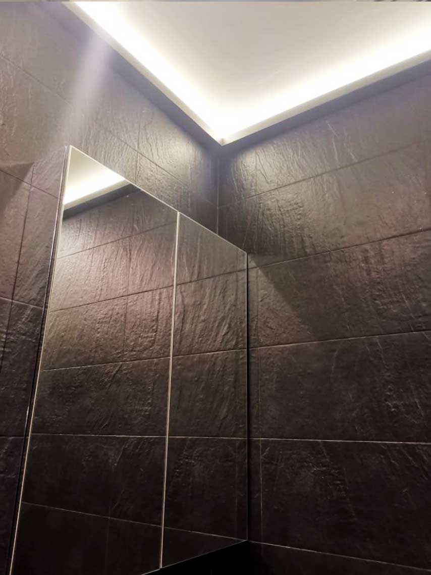 Salle de bain en pierre foncée avec corniche lumineuse LED — rénovation Paris