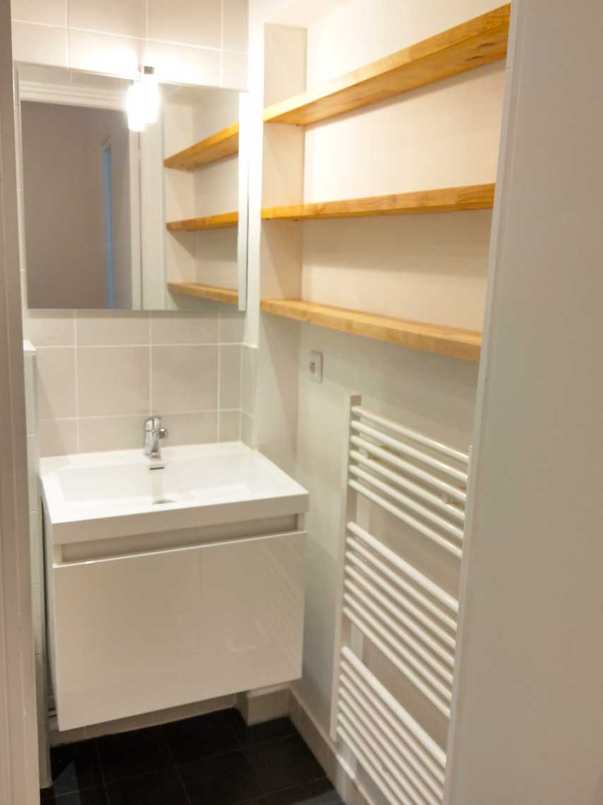 Salle de bain avec meuble blanc et étagères en pin — rénovation Paris