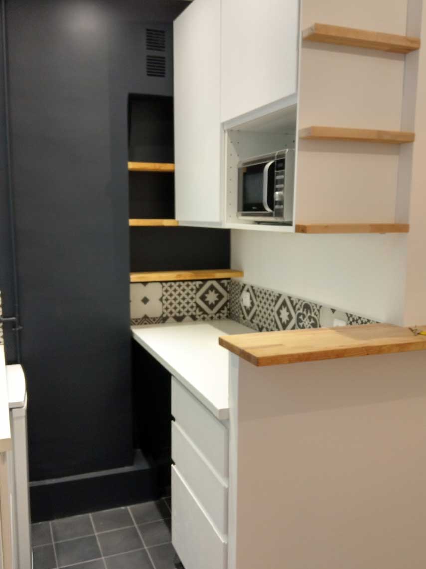 Cuisine avec mur noir et étagères en bois — rénovation Paris