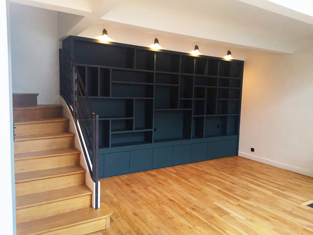 Séjour avec bibliothèque bleu navy et escalier — rénovation Paris